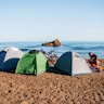 a person sitting next to a couple of tents on a beach